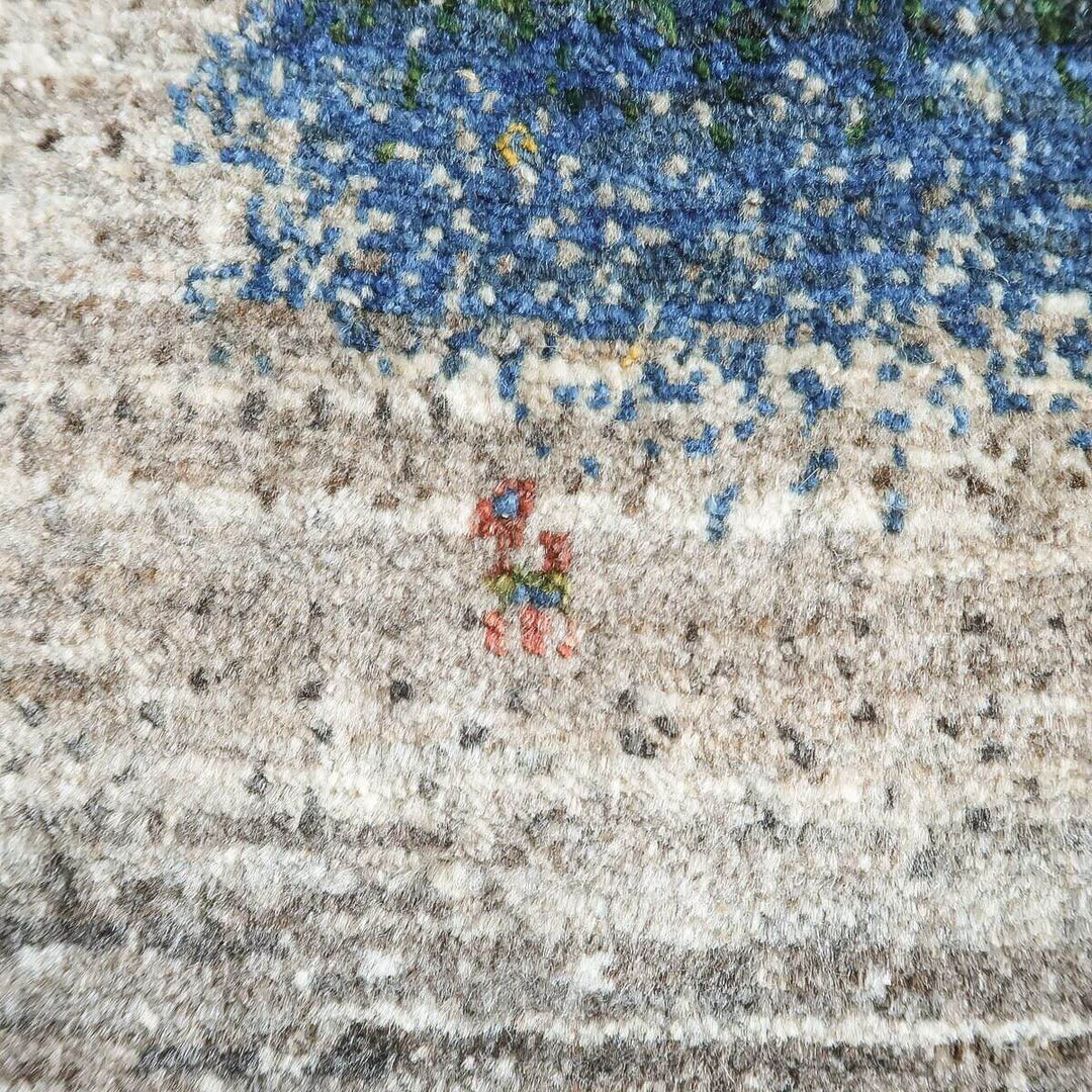 丁寧に手織りされたウールのペルシャ絨毯が、青とベージュの繊細な模様を描き出し、専門店の通販で見つかるギャッベラグの織り目が際立っている。