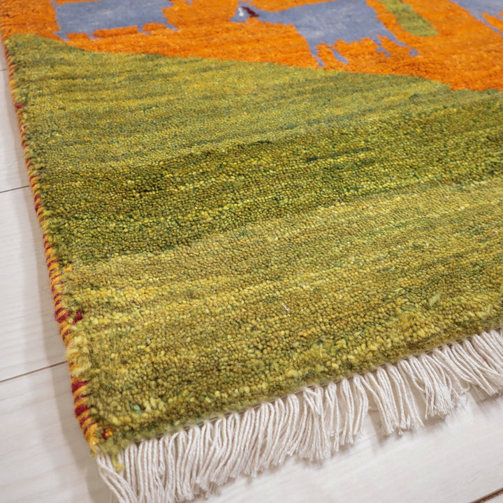 手織りのウールで丁寧に作られたギャッベラグの織り目が、ペルシャ絨毯専門店で通販される美しい緑とオレンジのグラデーションが床に映えている。