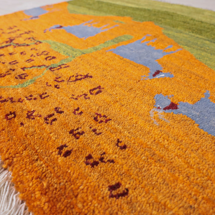 温かみのあるオレンジとブルーの模様が美しい手織りのギャッベラグが床に広がり、ウールの柔らかな質感が際立っている。