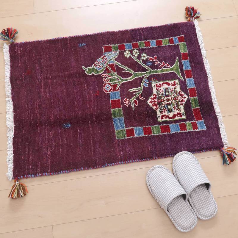 鮮やかな赤紫の手織りギャッベラグが床に敷かれ、ペルシャ絨毯専門店ならではの伝統的なデザインが際立っています。