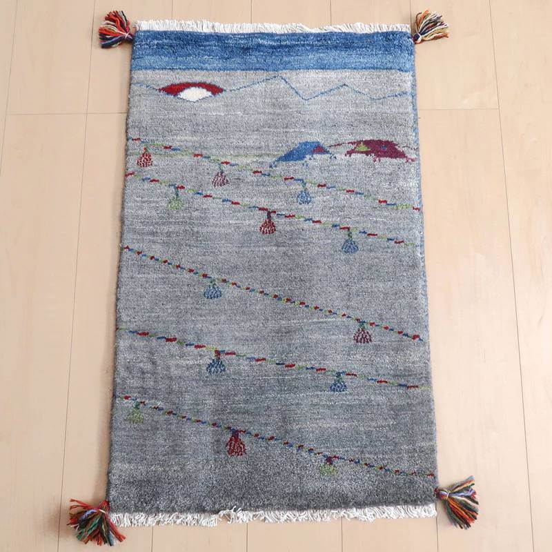 ギャッベ／ルリバフ 85×53cm（HSS-71723）は、カラフルなタッセルがアクセントになった、青と灰色の手織りギャッベラグが床に広がり、温かみと落ち着きを感じさせる。