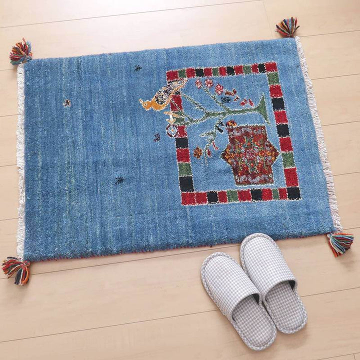 青い手織りのギャッベラグが木目の床に敷かれ、ペルシャ絨毯専門店ならではの伝統的な模様が細やかに織り込まれている。