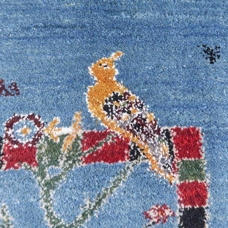 青を基調にしたウールのギャッベラグに、鳥と花のモチーフが丁寧に手織りで描かれたデザインが際立っている。