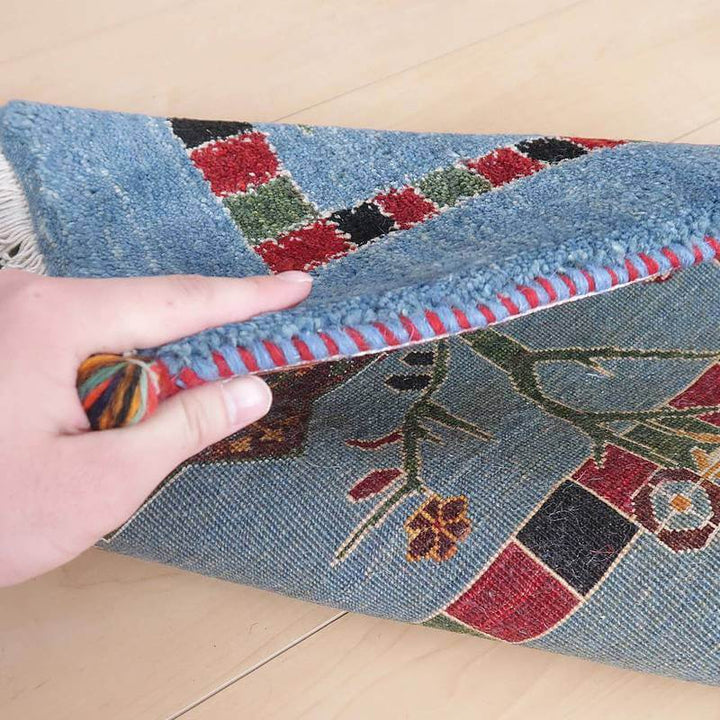 手織りのウール素材で丁寧に作られたギャッベラグがめくられ、その厚みと模様の美しさが際立っている。