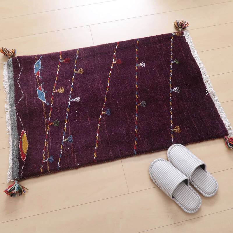 深いボルドー色の手織りギャッベラグが床に敷かれ、ペルシャ絨毯の伝統的な模様が色鮮やかに映えている。