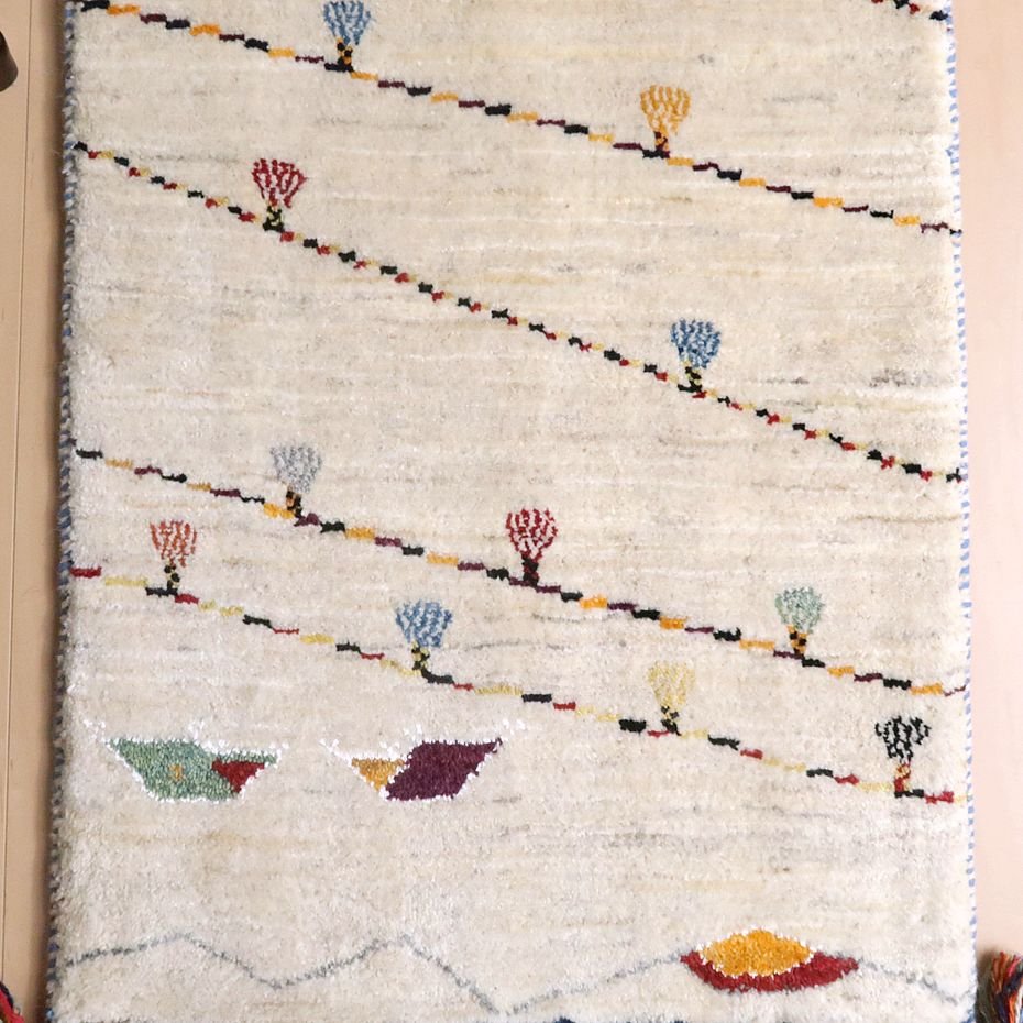 手織りのウールで仕上げられたギャッベのラグが、ペルシャ絨毯専門店の通販で購入できる、暖かみのある模様が並ぶ床に敷かれている。