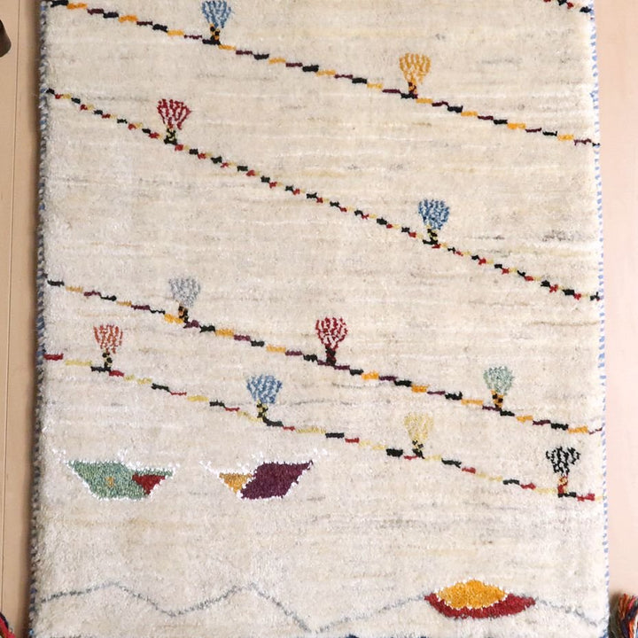 手織りのウールで仕上げられたギャッベのラグが、ペルシャ絨毯専門店の通販で購入できる、暖かみのある模様が並ぶ床に敷かれている。