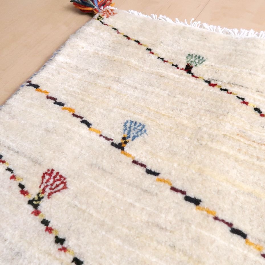 温かみのあるウール素材の手織りギャッベラグが、色とりどりの模様とともに床に柔らかく敷かれている。