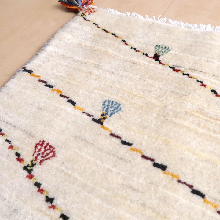 温かみのあるウール素材の手織りギャッベラグが、色とりどりの模様とともに床に柔らかく敷かれている。