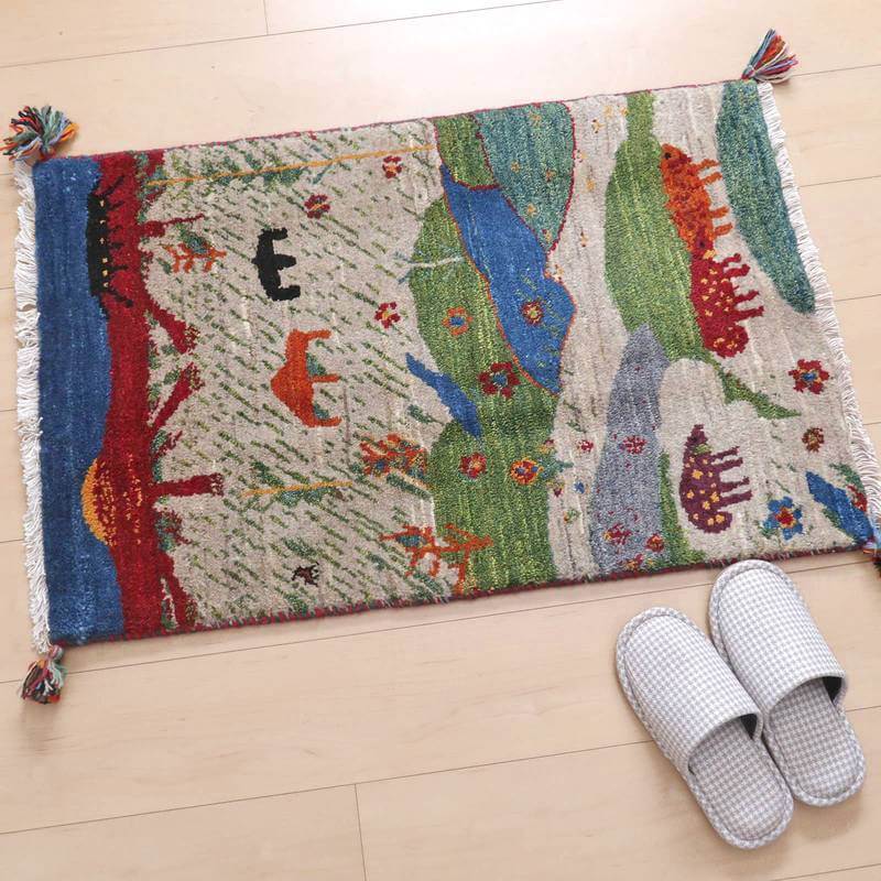 色とりどりの動物や自然模様が丁寧に手織りされたウールのギャッベラグが、玄関に温かみを添えて敷かれている。