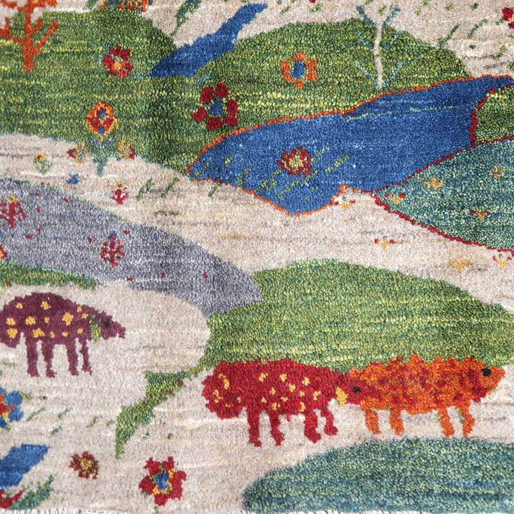 手織りのギャッベラグには、ウール素材で描かれた色鮮やかな草原と動物の模様が広がり、ペルシャ絨毯専門店の通販で見つかる温かみが感じられるデザインが見える。