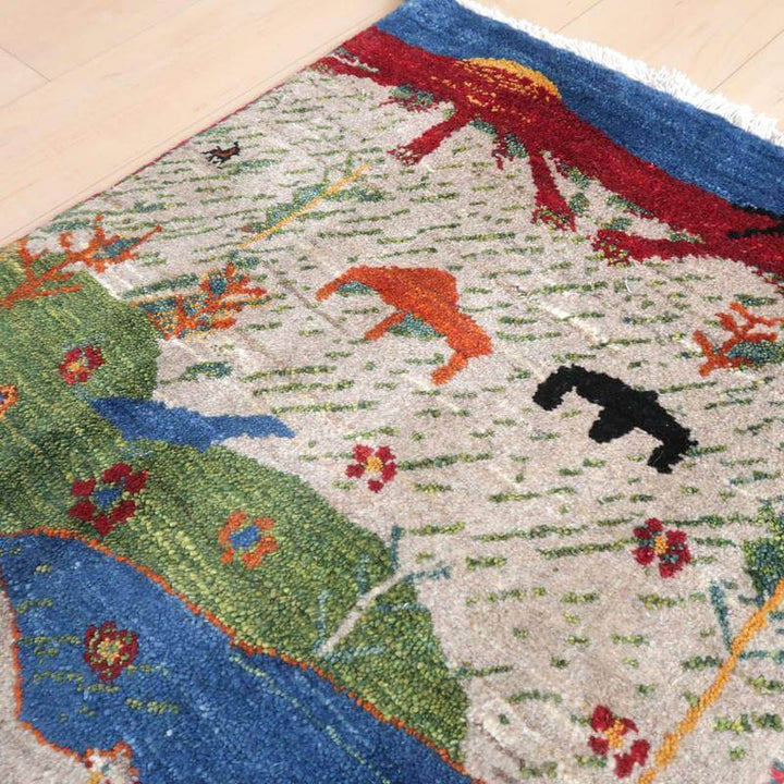 色鮮やかな動植物が丁寧に手織りされたギャッベのラグが、ウール素材の温かみを感じさせるように床に広がっている。