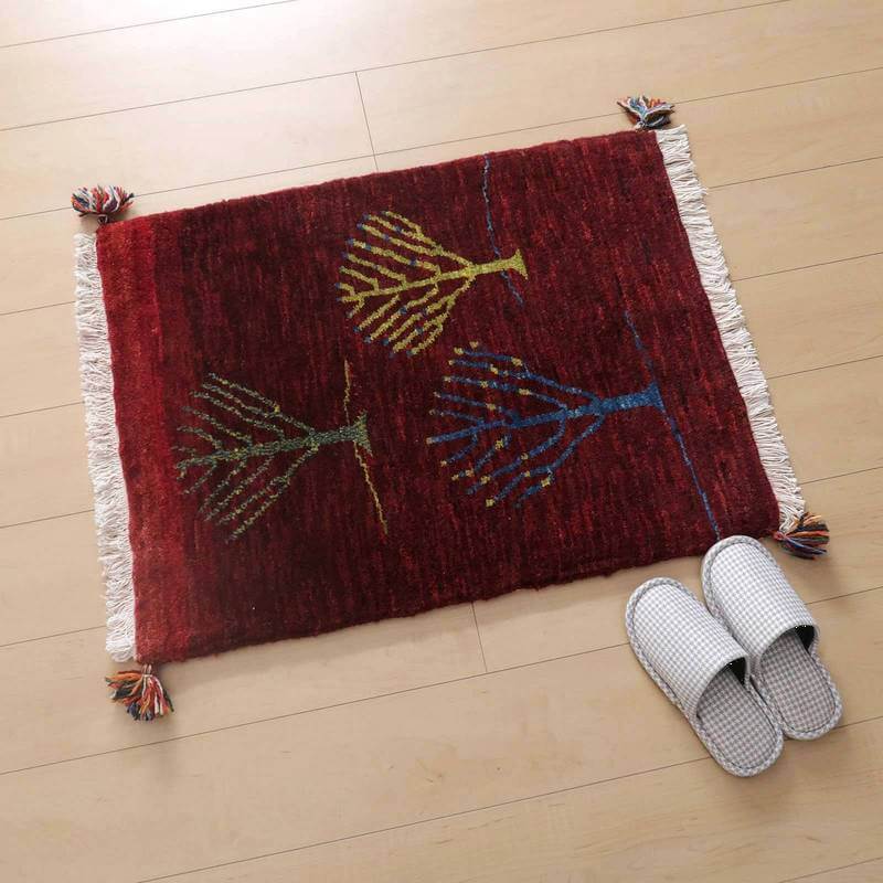 ぬくもりある赤いウールのギャッベラグが木目調の床に置かれ、手織りの模様がペルシャ絨毯専門店の通販で人気を集めています。