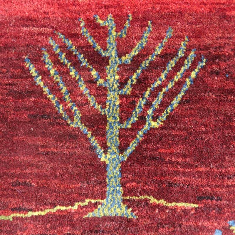 赤を基調にしたペルシャ絨毯のギャッベラグは、手織りのウールで丁寧に描かれた木のモチーフが印象的に浮かび上がっています。