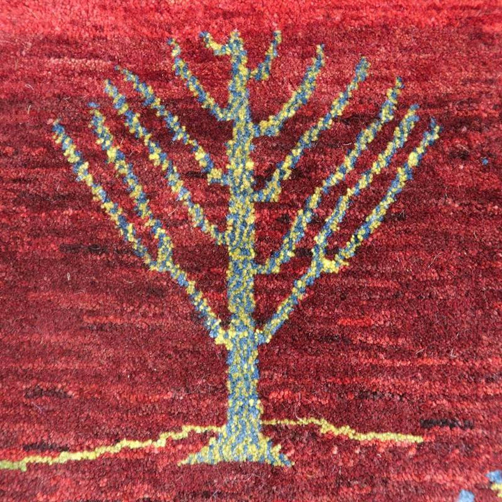 赤を基調にしたペルシャ絨毯のギャッベラグは、手織りのウールで丁寧に描かれた木のモチーフが印象的に浮かび上がっています。