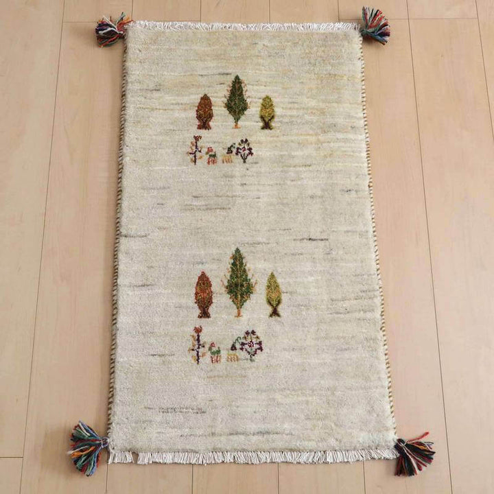 ギャッベ／ルリバフ 87×52cm（HSS-71497）は、手織りのウール製ギャッベラグが床に敷かれており、ペルシャ絨毯専門店の通販で購入可能な、温かみのある木々のモチーフが魅力的に映えています。