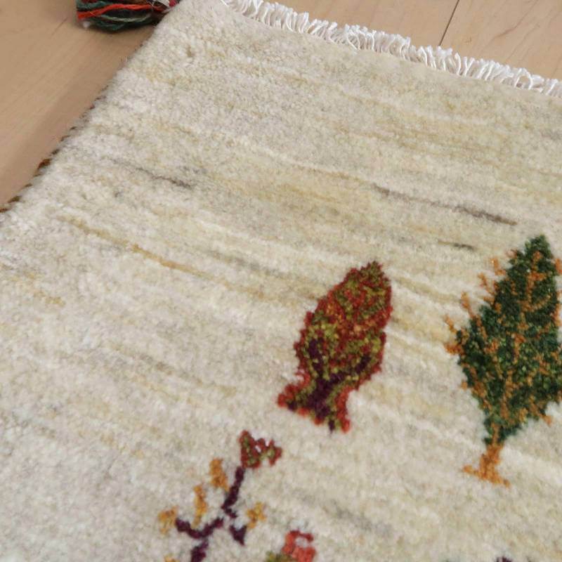 ナチュラルなウール素材に手織りで丁寧に描かれた色鮮やかな植物模様が魅力のギャッベラグが床に広がっている。