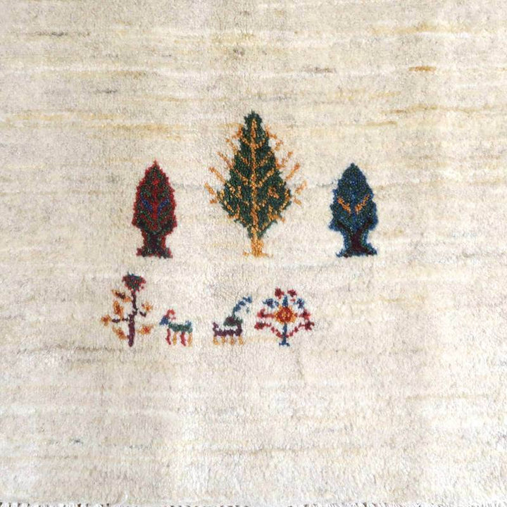 手織りのペルシャ絨毯専門店から通販で購入できる、ウール素材のギャッベラグには、自然をモチーフにした木と動物の柄が丁寧に織り込まれている。