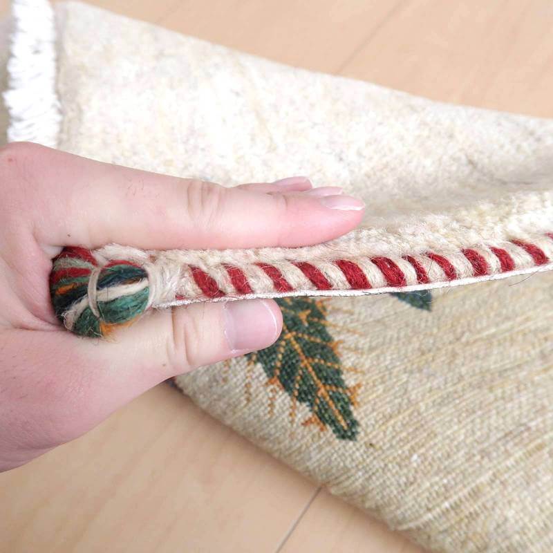 手織りのギャッベラグが持ち上げられ、ウール素材の厚みとペルシャ絨毯らしい赤い縁取りが際立っている。