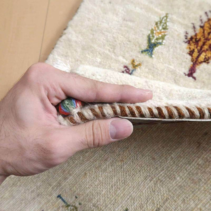 手織りのギャッベラグの厚みがしっかりと感じられるウール素材の縁がめくられている。