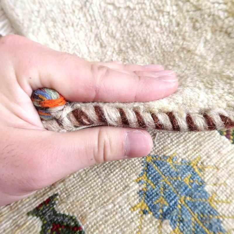 手織りのギャッベラグの厚みと織り目の密度が手に取られ、ウールの柔らかさとペルシャ絨毯の伝統が感じられる。