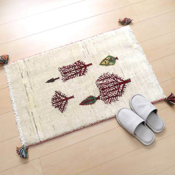 手織りのウール素材で丁寧に作られたペルシャ絨毯専門店のギャッベラグが、木の模様とともに明るい床に敷かれている。