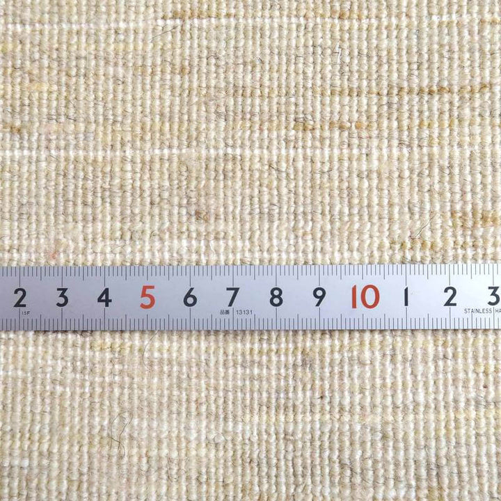 手織りのぬくもりが感じられるウール製ギャッベラグの織り目を定規で示したクローズアップが見える。