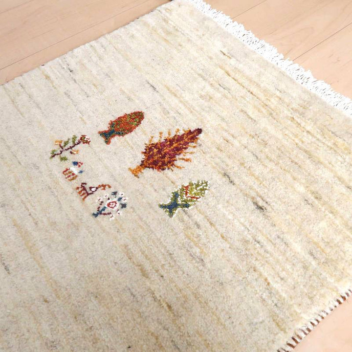 木目調の床に敷かれた、鮮やかなモチーフが描かれたペルシャ絨毯専門店の手織りギャッベラグが見える。