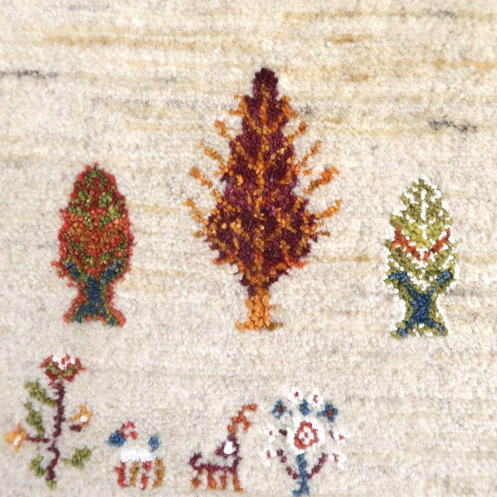 手織りのギャッベラグの接写で、温かみのあるウール素材に緻密に描かれた木々と動物の模様が際立っています。