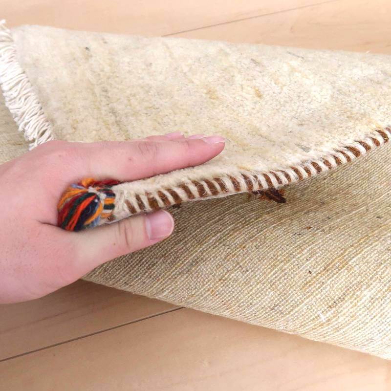 手織りのウール素材で丁寧に仕上げられたギャッベラグが、柔らかな風合いとともにその裏面の織り目がめくられている。