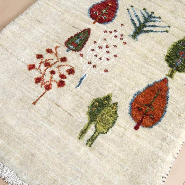 手織りのギャッベラグが床に広がり、ペルシャ絨毯の専門店から通販されたウール素材の温かみのある葉の模様が際立っている。