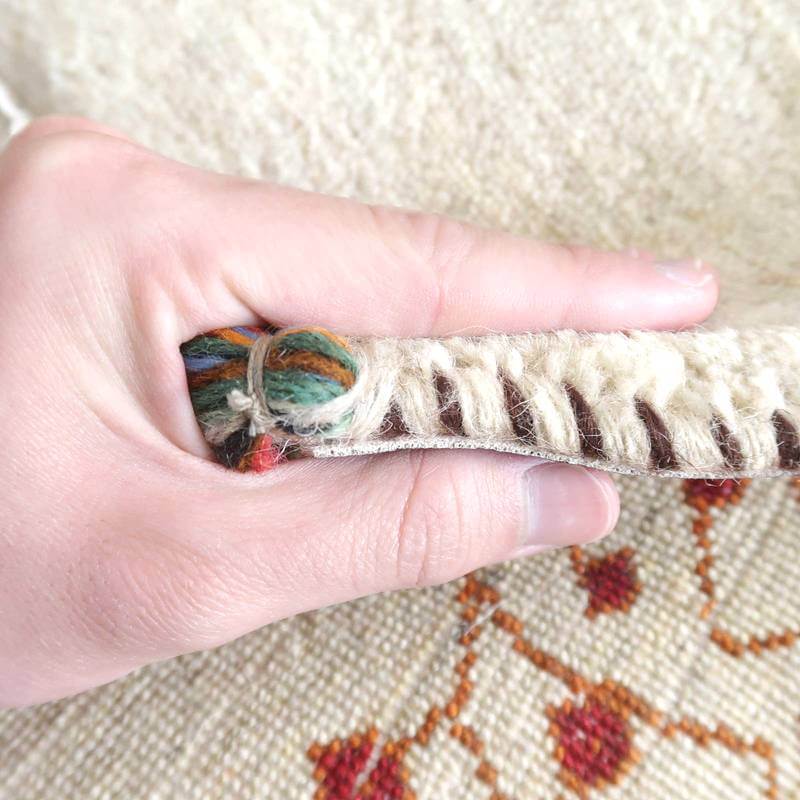 手織りのギャッベラグの厚みと織り目が指先で確認できるこのウール素材の一枚は、温かみのあるペルシャ絨毯専門店の通販商品です。