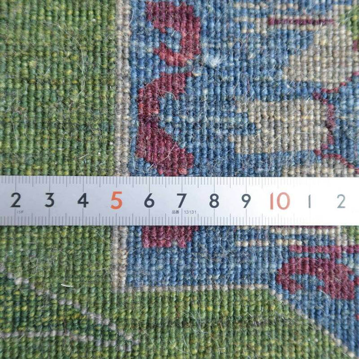 手織りのウール製ペルシャ絨毯の織り目が細かく、緑と青の色彩が美しいギャッベラグが定規とともに見える。