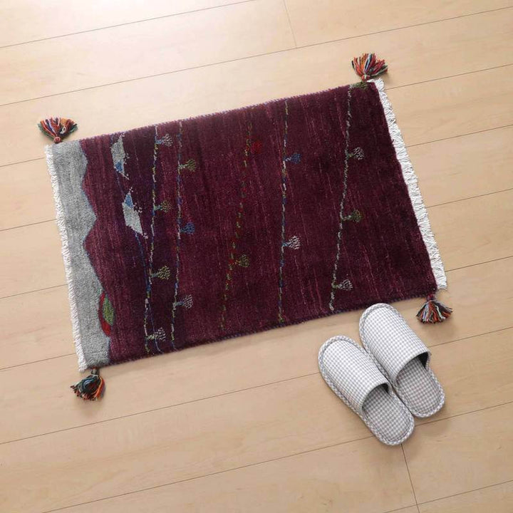 深みのある赤色の手織りギャッベラグが木目の床に敷かれ、端に飾られたタッセルとともにぬくもりを添えている。