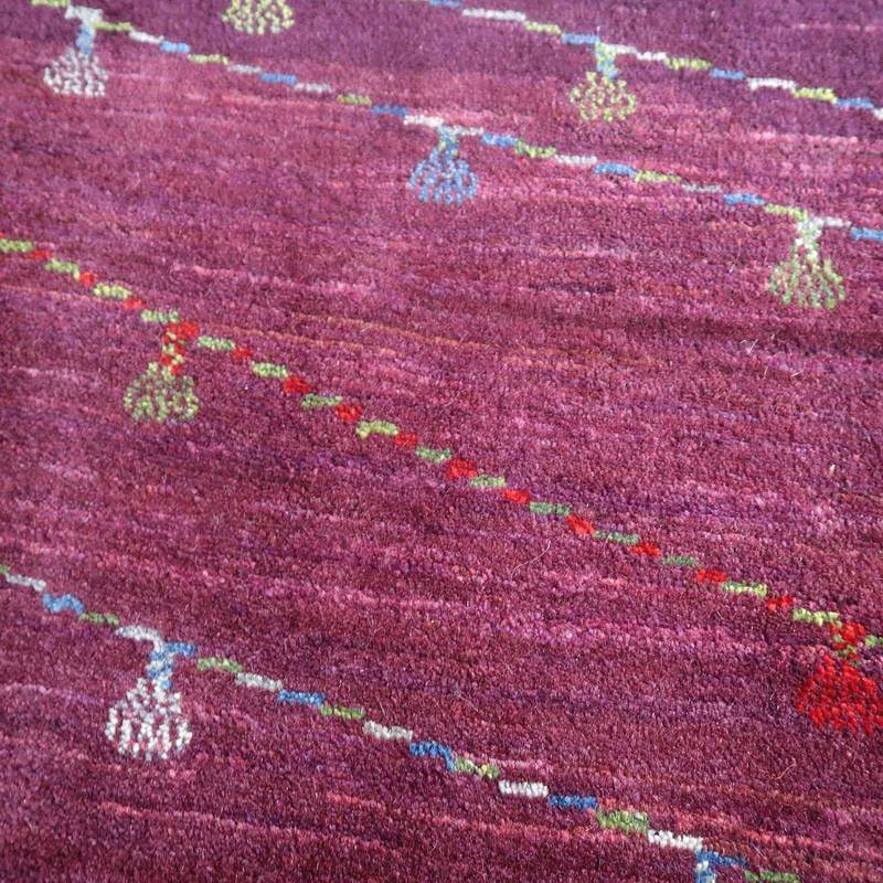 深みのあるパープルのウール製ギャッベラグに、色とりどりの模様が丁寧に手織りで描かれているのが見える。