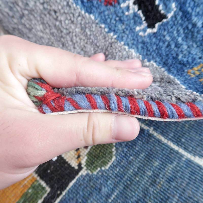 手織りのペルシャ絨毯ギャッベの厚みと織り目の細かさが際立ち、ウール素材の柔らかな質感が指先に伝わる。