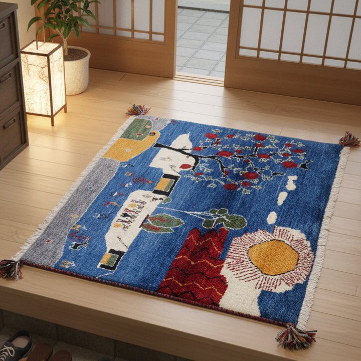色鮮やかな青地に自然モチーフが丁寧に描かれた手織りのギャッベが、ウールの温かみを感じさせつつ床に広がっています。