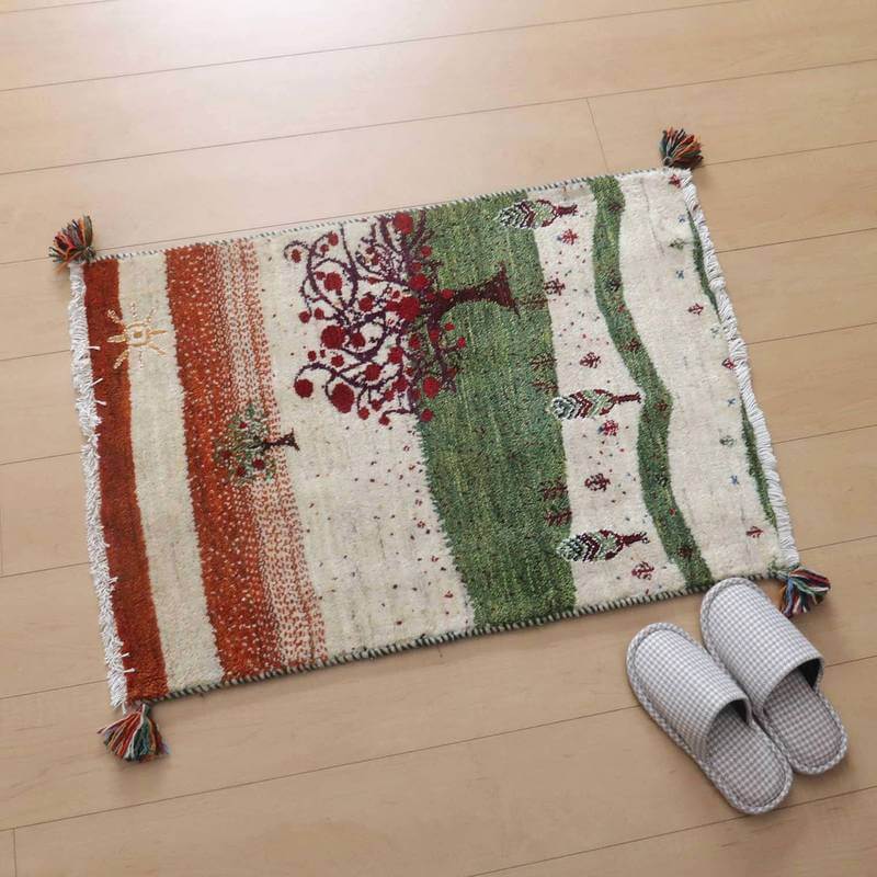 ぬくもりある手織りのギャッベラグが、玄関の木目床に敷かれ、赤と緑の模様がペルシャ絨毯のような風合いを醸し出している。