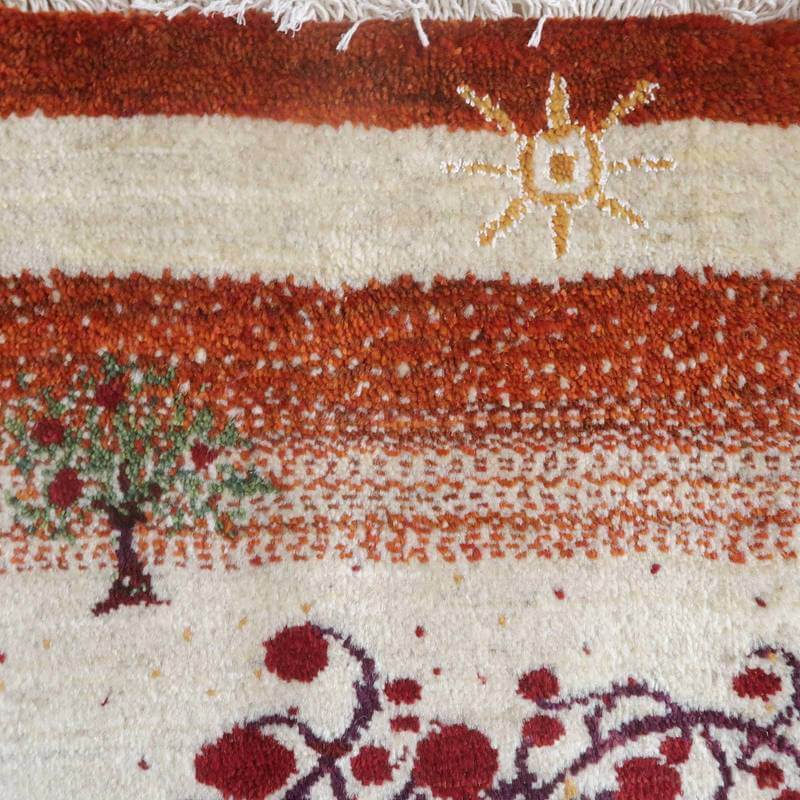 太陽と木が丁寧に織り込まれた赤と白の手織りギャッベラグは、ぬくもりを感じさせるデザインが際立っている。