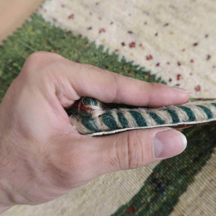 手織りのギャッベラグが丁寧に巻かれ、その厚みと柔らかなウール素材が手にしっかりと感じられる。