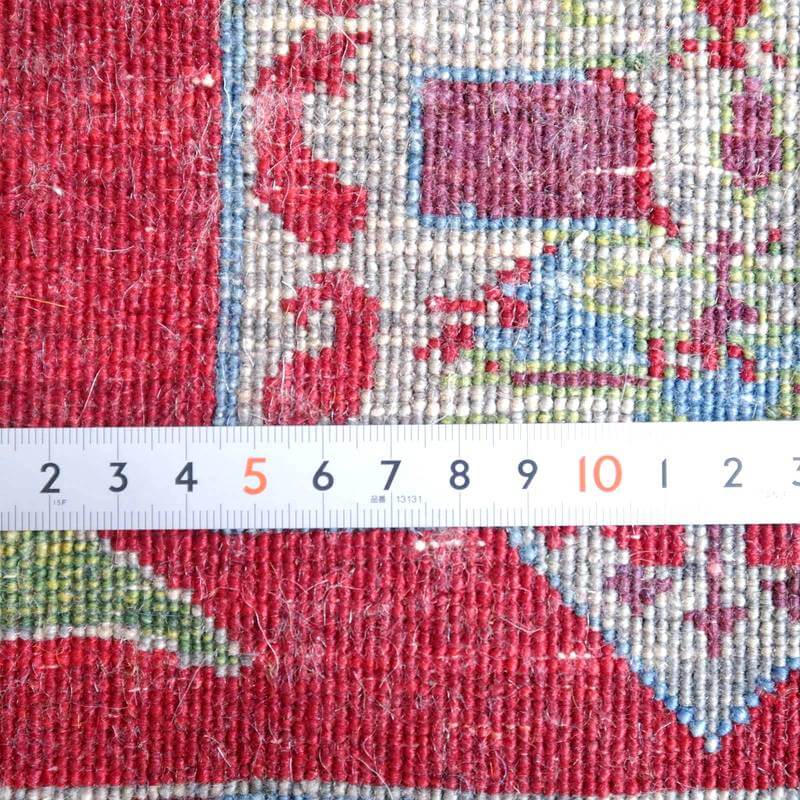 赤を基調としたペルシャ絨毯のギャッベが、手織りの織り目の細やかさをメジャーとともに見せている。