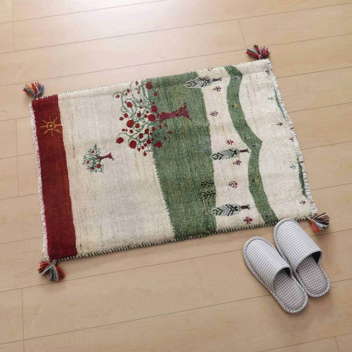 手織りのウールで作られたこのギャッベ・ラグは、ペルシャ絨毯の専門店で通販可能で、木と動物のモチーフが温かみを添えて床に敷かれている。