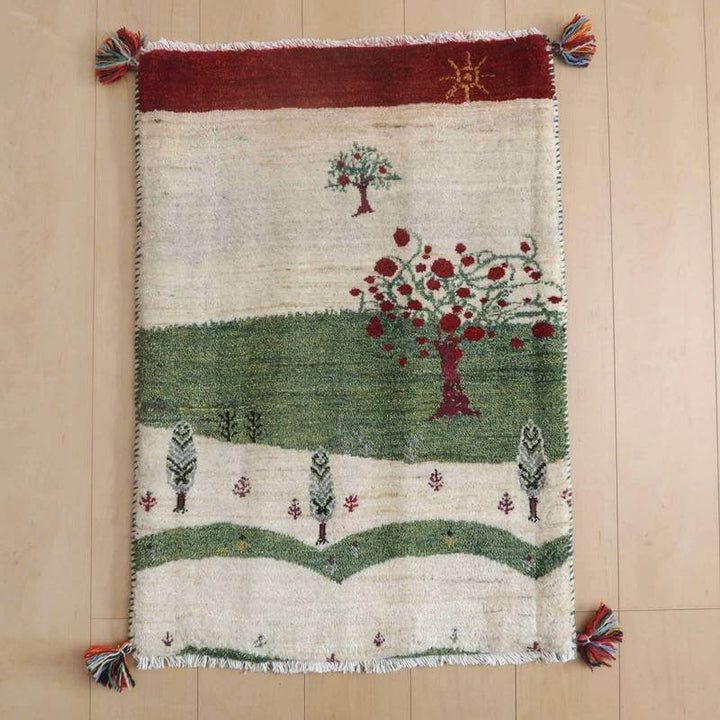 ギャッベ／ルリバフ 90×63cm（HSS-71767）は、緑と赤の木々が描かれた手織りウールのギャッベラグが、ペルシャ絨毯専門店の通販で提供される温かみあるデザインが床に広がっている。