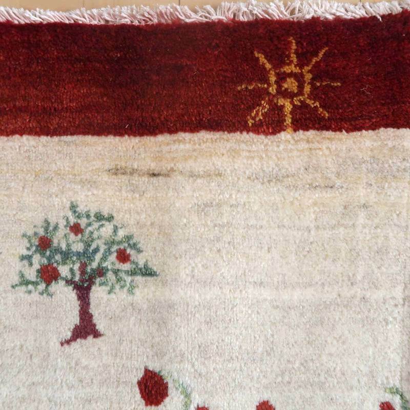 手織りのギャッベラグが、暖かなウール素材でペルシャ絨毯専門店の通販で人気のデザインとして、豊かな木と太陽のモチーフが際立っている。