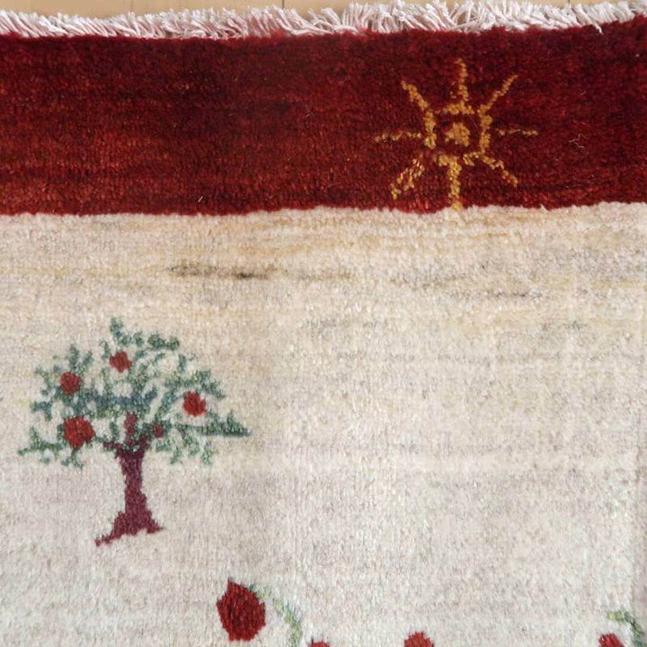 手織りのギャッベラグが、暖かなウール素材でペルシャ絨毯専門店の通販で人気のデザインとして、豊かな木と太陽のモチーフが際立っている。