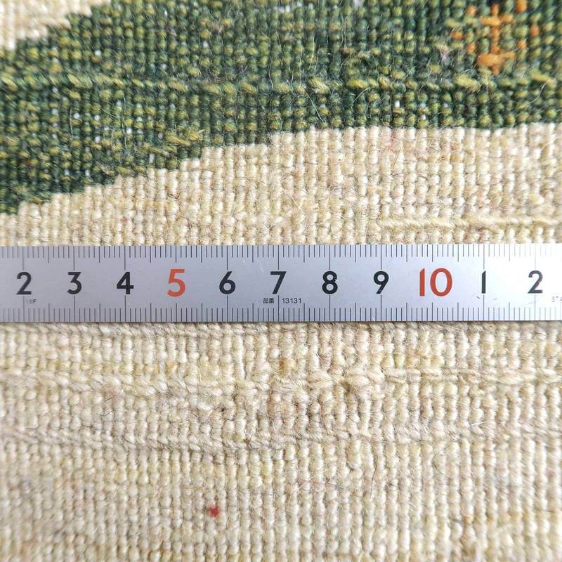 手織りのペルシャ絨毯専門店が通販するウール製ギャッベの細やかな織り目を、定規とともに接写で捉えた一枚。