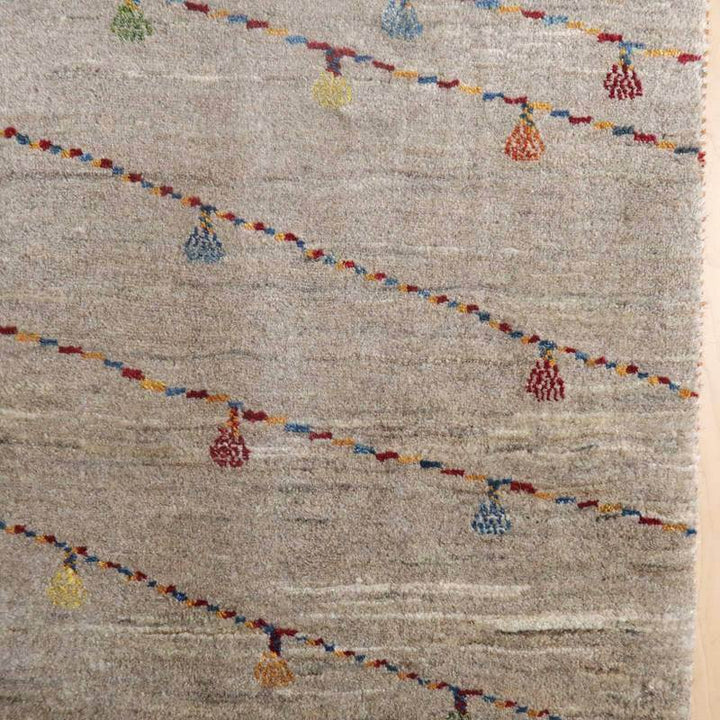 色とりどりの模様が斜めに配された手織りのウール製ギャッベラグが床に広がり、柔らかな風合いが際立っています。