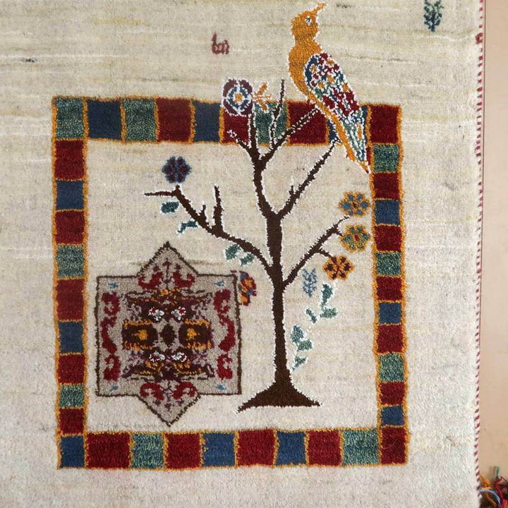 手織りのウール素材で丁寧に仕上げられたペルシャ絨毯専門店のギャッベラグには、カラフルな鳥と木のモチーフが描かれている。
