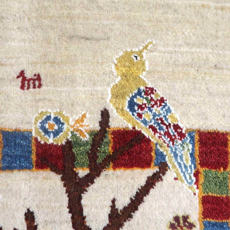 手織りのギャッベラグには、色鮮やかな鳥と木のデザインが丁寧に描かれ、ペルシャ絨毯専門店の通販で見つかるウールの織り目が際立っています。