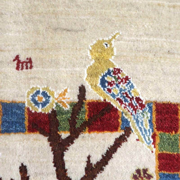 手織りのギャッベラグには、色鮮やかな鳥と木のデザインが丁寧に描かれ、ペルシャ絨毯専門店の通販で見つかるウールの織り目が際立っています。